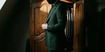 A person adjusting a tailored dark green blazer, viewing their wardrobe as a strategic asset for professional first impressions and economic value.
